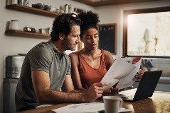 A man and a woman reviewing financial inforamtion on a laptop iStock-1163500880