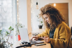 A young woman using a credit card to shop online using a laptop