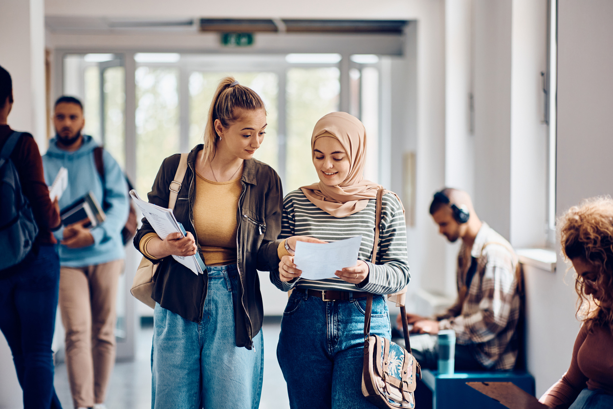 Female students going through lecture notes while walking through the hallway