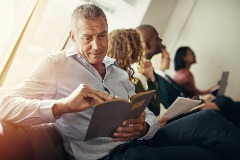 A mature man reading information on a tablet