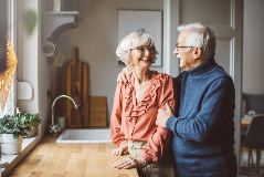 Old couple at kitchen counter smiling at each other
