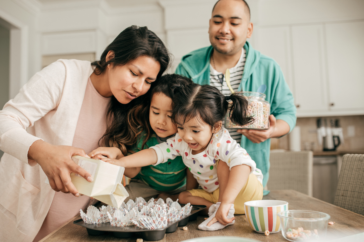 Two parents and two children baking together in a kitchen